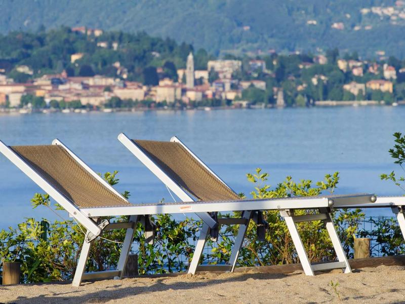 Two empty lounge chairs by the lake with a city view in the background.