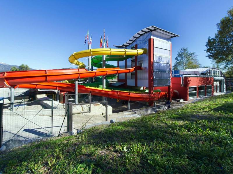 Slide facility with two colorful water slides and red buildings under blue sky.