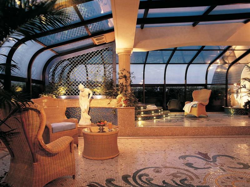 Véranda élégante avec mobilier rembourré, plantes et sol en mosaïque décorée dans un hôtel.