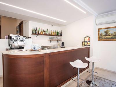 Moderner Hotelbarbereich mit Holztresen, weißen Barhockern und Kaffeemaschine.