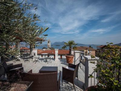 Terrasse mit Holzmöbeln, Pflanzen und Blick auf rote Dächer unter bewölktem Himmel.