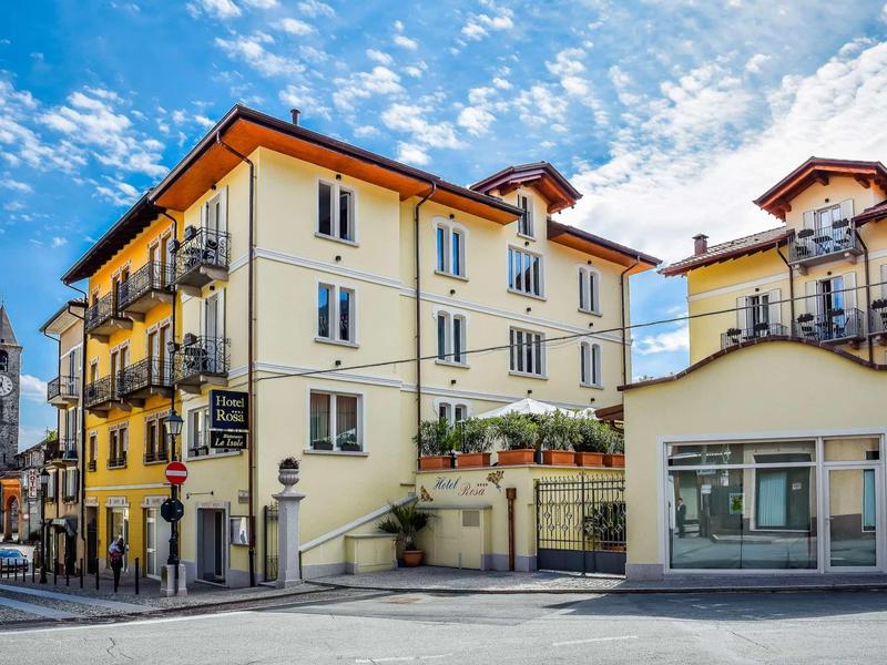 Mehrstöckiges gelbes Wohngebäude mit roten Dachziegeln und Balkonen unter blauem Himmel.