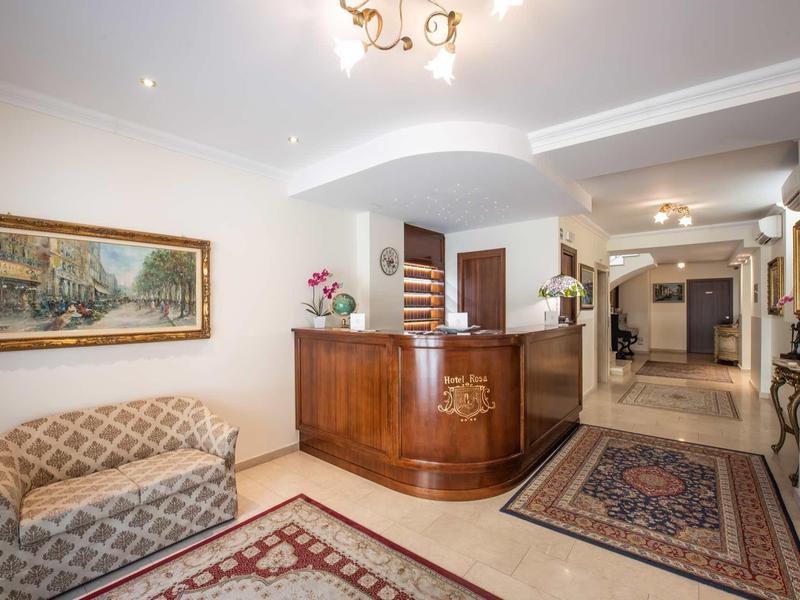 Schicker Empfangsbereich mit Holztresen, Gemälde, gemusterten Teppichen und einem Sofa mit Kissen.