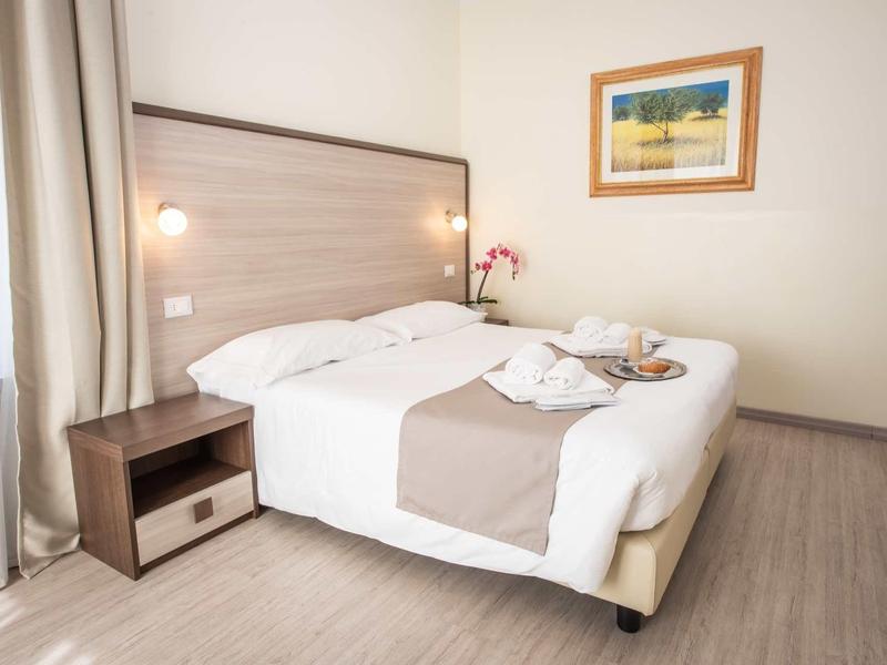 Gemütliches Schlafzimmer mit Doppelbett, Holzboden, Nachttisch, Vorhängen und Wandbild.