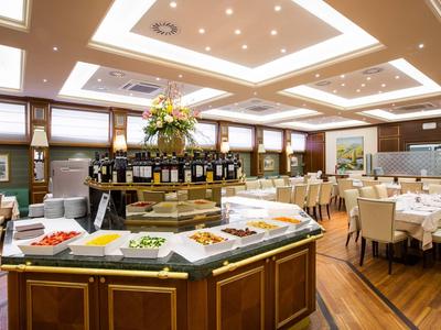 Elegantes Restaurant mit Buffetinsel, hellen Stühlen und warmem Holzfußboden.