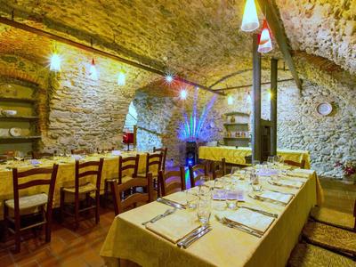 Gemütlicher Gewölbekeller mit langen, gedeckten Tischen, Holzbalken und warmem Licht.