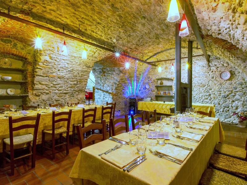 Gemütlicher Gewölbekeller mit langen, gedeckten Tischen, Holzbalken und warmem Licht.