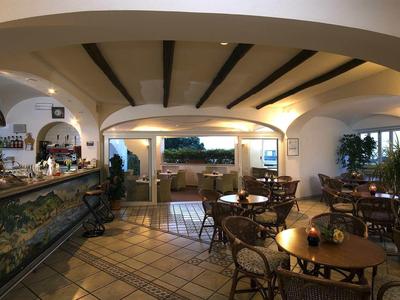 Gemütliches Restaurant mit Holztischen, Stühlen und großer Fensterfront mit Blick ins Freie.