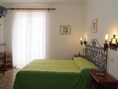 Camera da letto con un letto matrimoniale, copriletto verde e lampade da parete antiche.