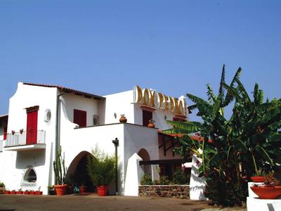 Edificio bianco con porte rosse e giardino sotto un cielo azzurro limpido.