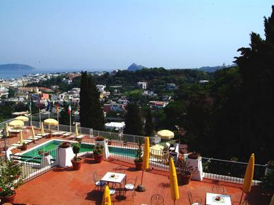 Vista di una terrazza con tavoli e ombrelloni, una piscina sullo sfondo e il mare in lontananza.