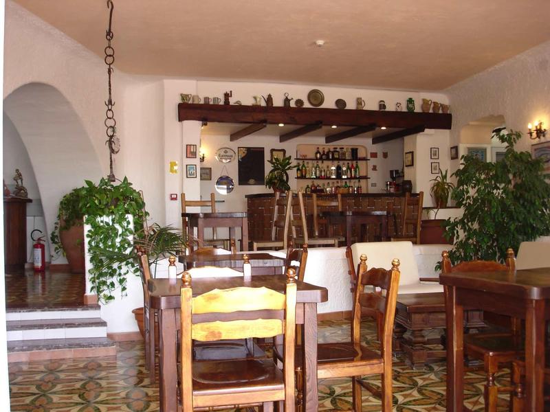 Accogliente area bar e salotto dell'hotel con sedie di legno, piante e pavimento decorativo