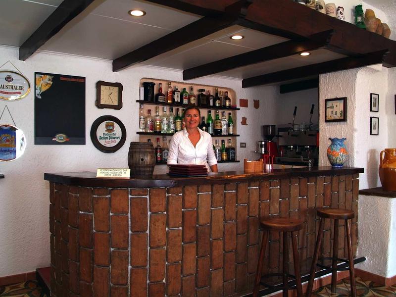 Addetta alla reception dietro un bancone rustico in legno in un'accogliente area dell'hotel.