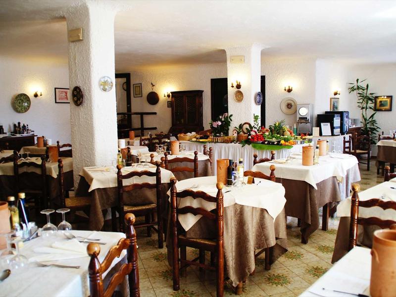 Sala da pranzo luminosa con tovaglie bianche e sedie di legno in un ristorante accogliente.