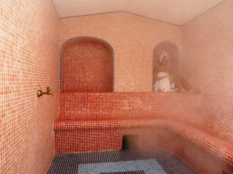 Red mosaic steam room with benches and statue in niche