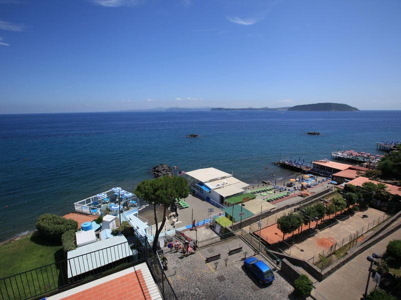 View of a coastline with clear sky, blue sea, and small buildings along the shore.