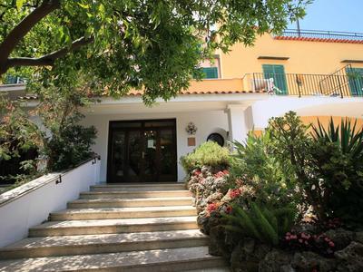 Entrée d'hôtel avec escaliers, plantes et lumière du soleil.