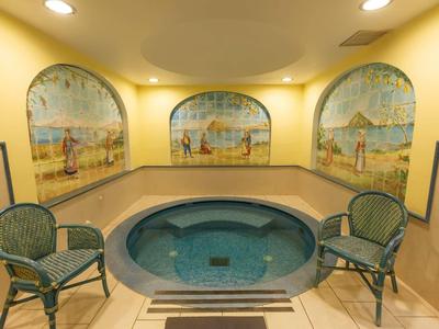 Petit bain à remous rond avec deux chaises et fresques murales dans un espace bien-être.