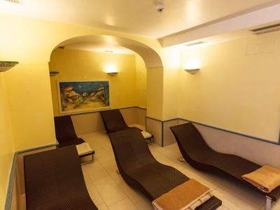 Salle de détente avec chaises longues, lumière chaude et murs jaunes dans un hôtel.