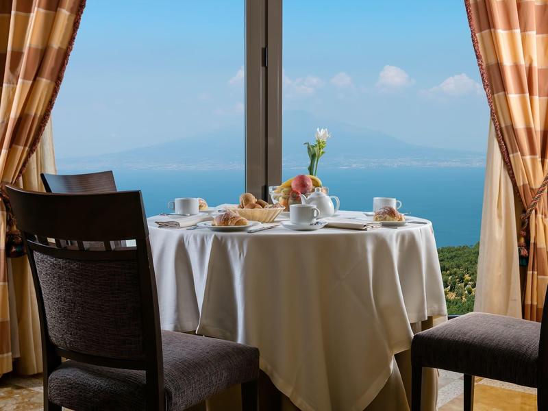 Runder Tisch mit Frühstück vor Panoramafenster mit Blick auf das Meer
