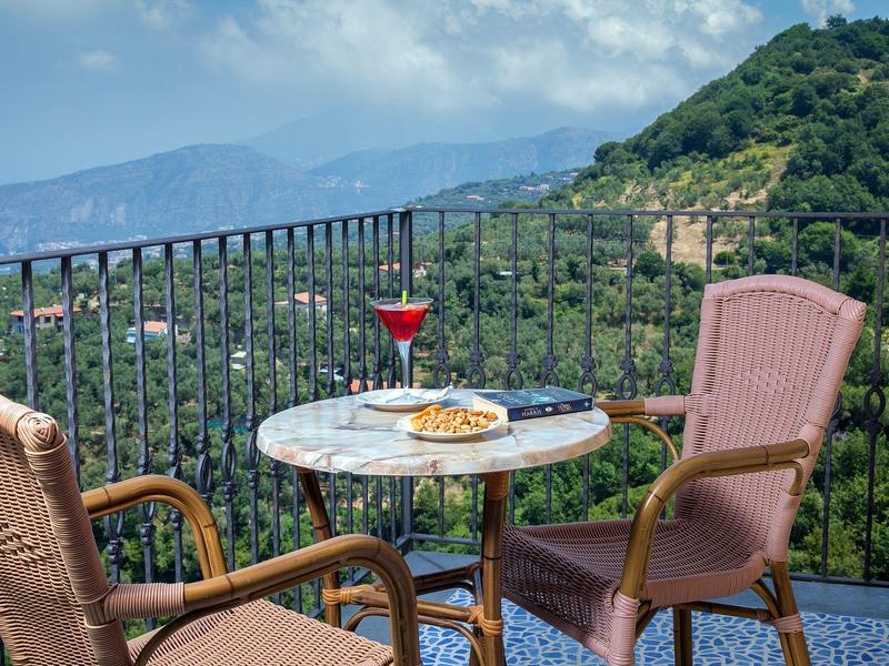 Balkon mit zwei Stühlen, Marmor-Tisch, Drink und Snacks mit Bergblick.
