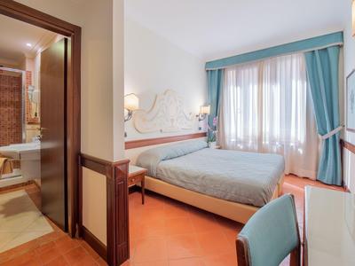 Kleines Hotelzimmer mit Doppelbett, blauem Vorhang und angrenzendem Bad.