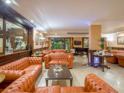 Hotel-Lounge mit orangefarbenen Ledersesseln, Tischen und kunstvoller Dekoration.