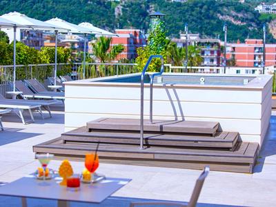 Moderne Hoteldachterrasse mit Pool, Liegestühlen und Getränken bei sonnigem Wetter.