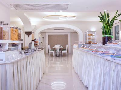 Heller Frühstücksraum mit Buffet und zentralem Sitzbereich in einem Hotel.