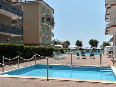 Poolbereich zwischen zwei Gebäuden mit Blick auf das Meer im Hintergrund.