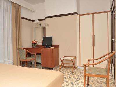 Een hotelkamer met een bureau, stoel, kast en eenvoudig houten meubilair.