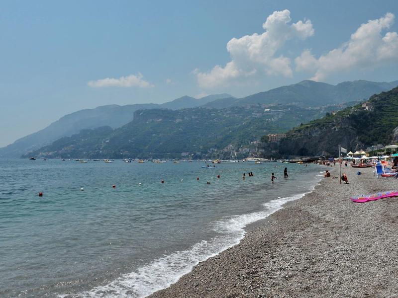 Strand met kiezelstenen, blauwe zee en bergen op de achtergrond op een zonnige dag