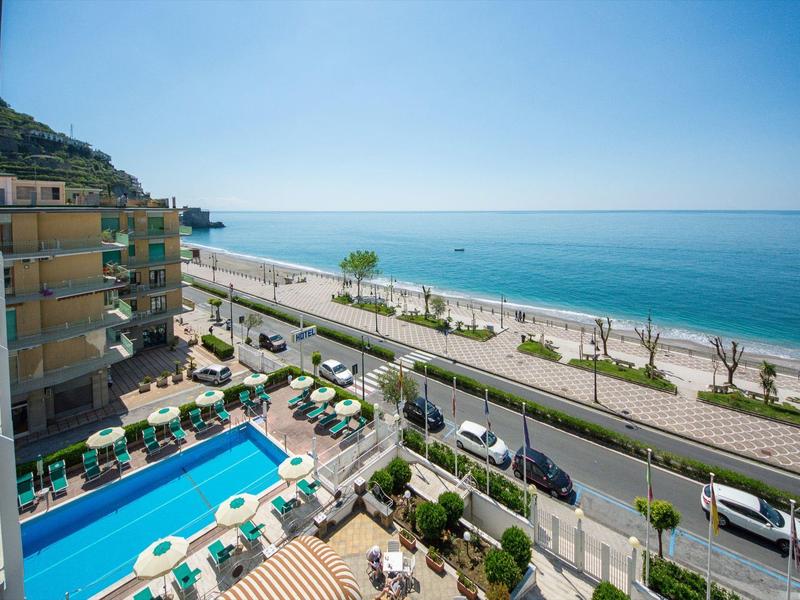 Uitzicht op een buitenzwembad, een weg en de zee op een zonnige dag.