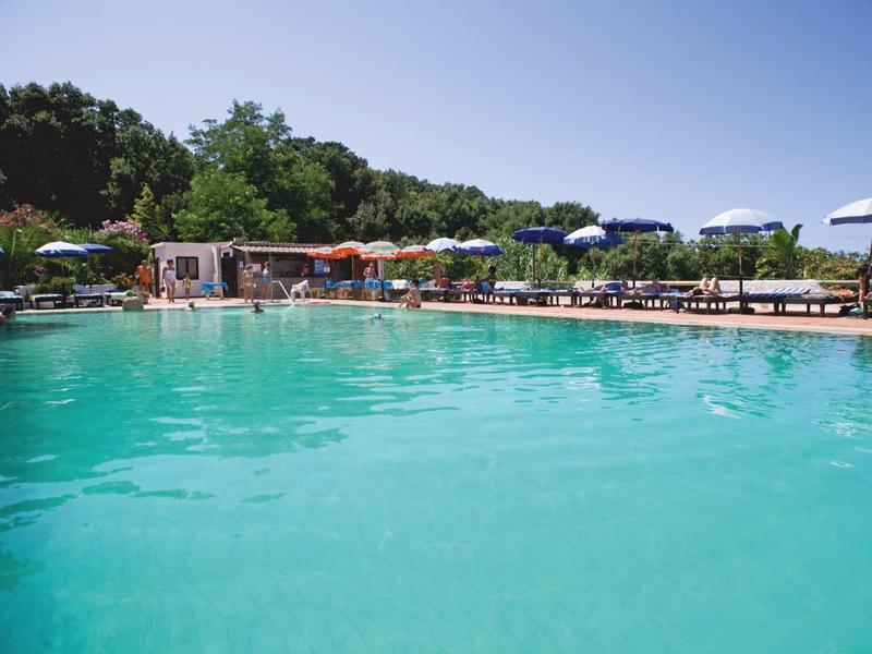 Großer Außenpool mit türkisfarbenem Wasser, umgeben von Liegestühlen und Sonnenschirmen.