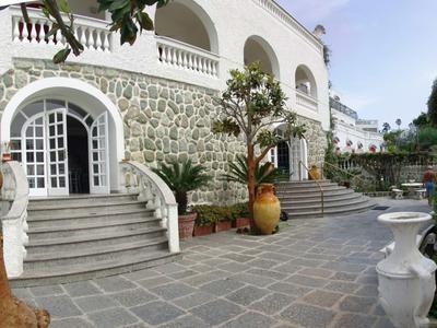 Edificio dell'hotel con pareti rivestite in pietra, archi bianchi e ampie scale davanti.
