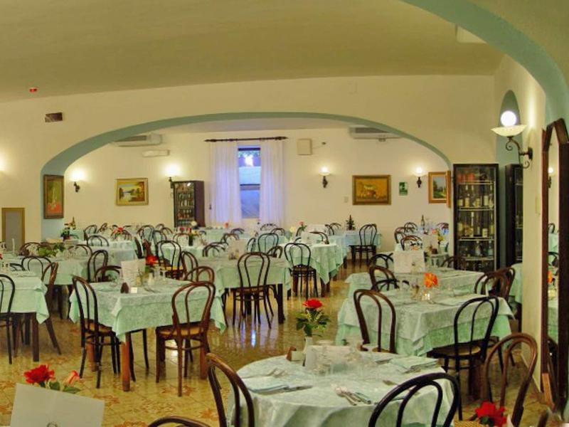 Grande sala da pranzo con molti tavoli apparecchiati e sedie in un ristorante.