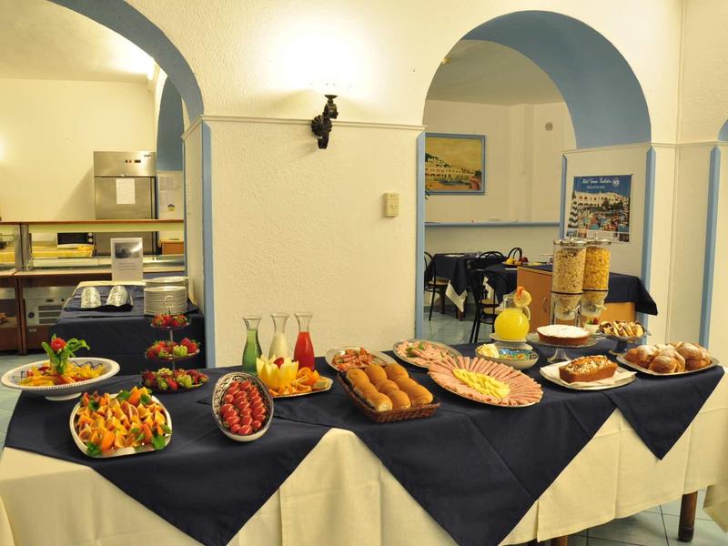 Buffet con vari cibi e bevande in una stanza luminosa con archi blu.