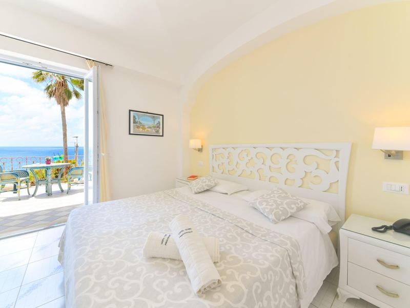 Lichte slaapkamer met tweepersoonsbed en uitzicht op terras en zee