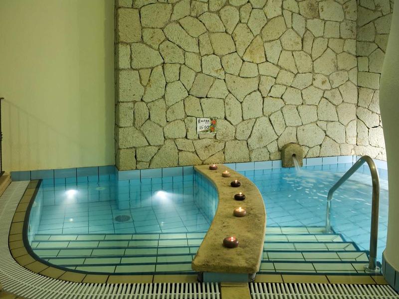 A luxury hot tub with stone steps and natural stone walls in a spa area.