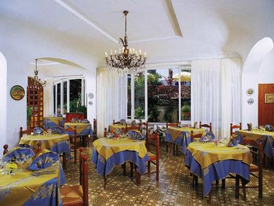 Gemütlicher Essraum mit blau-gelb gedeckten Tischen, Kronleuchter und großen Fenstern.