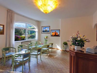 Hell eingerichteter Raum mit grün gepolsterten Stühlen, Tischen und Blumenarrangements.