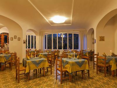 Leeres Restaurant mit Tischen, grün-gelben Tischdecken und Holzboden bei warmem Licht.