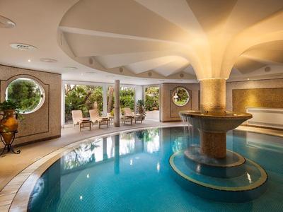 Kruhový vnitřní bazén se sloupem a poslechovou zónou v elegantním hotelovém prostředí.