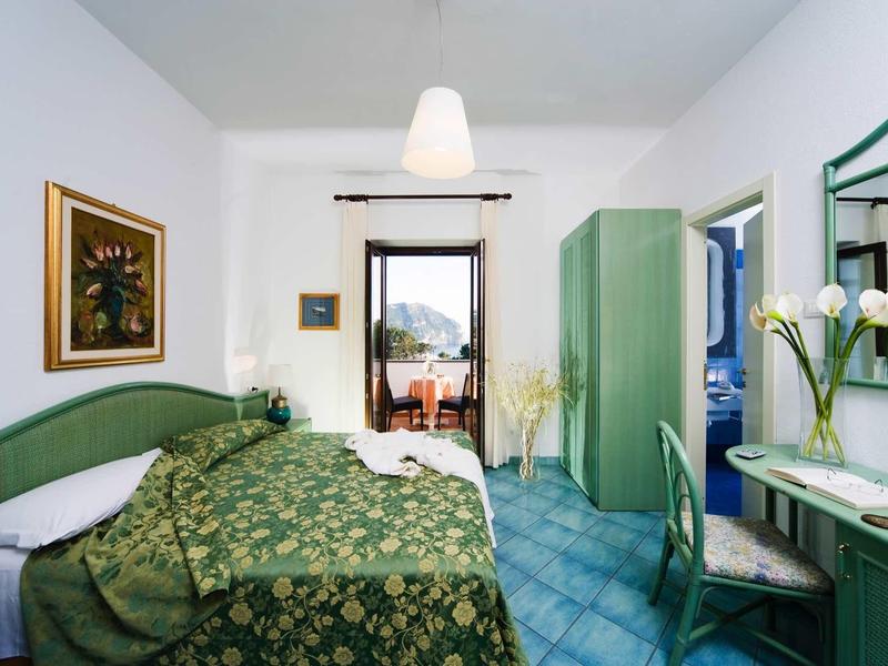 Gezellige hotelkamer met groen meubilair en balkon met uitzicht buiten.