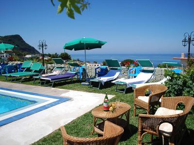 Poolbereich mit Liegen und Sonnenschirmen neben dem Meer bei klarem Himmel