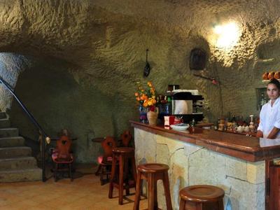 Rustikale Bar mit Holztheke und Steintreppe in einem gemütlichen Hotelinterieur.