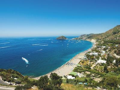 Côte avec eau bleue claire, plage de sable, trafic maritime et ville adjacente.