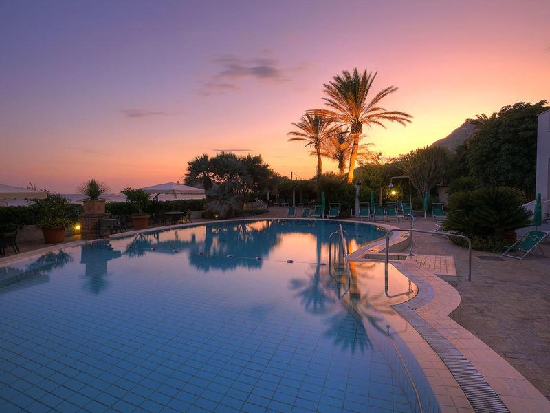 Oświetlony basen o zachodzie słońca z palmami i spokojnym otoczeniem.