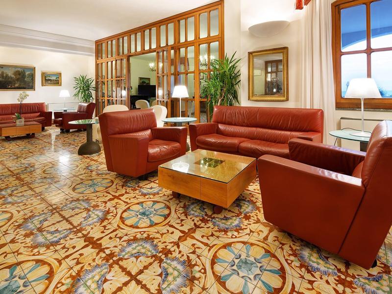 Elegancki hol hotelowy z czerwonymi skórzanymi fotelami i stylową wykładziną podłogową.