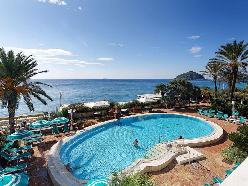 Basen hotelowy z leżakami i palmami z widokiem na morze i błękitne niebo